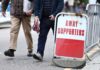 Football fans walk past an away supporters sign