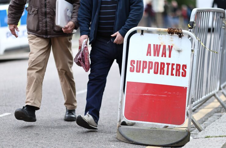 Football fans walk past an away supporters sign